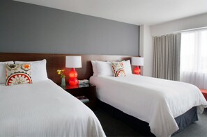 A hotel room with two beds, a nightstand, and a window with curtains.