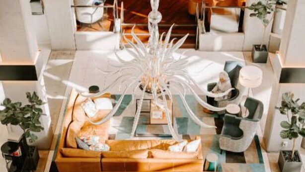 A modern lobby with a central seating area featuring a brown leather sofa and a unique white chandelier. - Patron Double + Exclusive Patron Lounge Access (Tacoma)