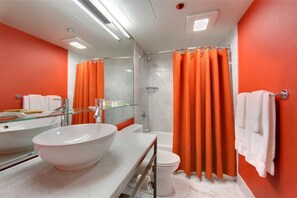 A modern bathroom with a large white sink, a glass shower enclosure, and an orange shower curtain. - Opulent Superior Suite + Breathtaking Art Paradise (Tacoma)
