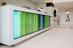 A reception area with a modern design, featuring a large, colorful vertical panel and a sleek, white reception desk. - Opulent Superior Suite + Breathtaking Art Paradise (Tacoma)