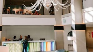 Un vestíbulo amplio con un candelabro moderno, una recepción y un área de estar.