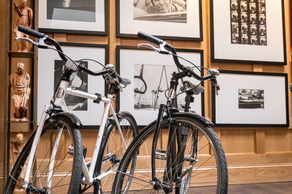 Bicycles parked in front of a wall with framed pictures.