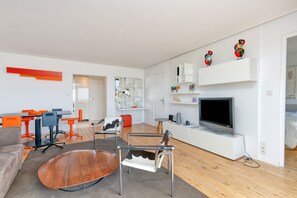 Un salon moderne comprenant un canapé, une table basse, un téléviseur et un coin repas avec des chaises et une table.
