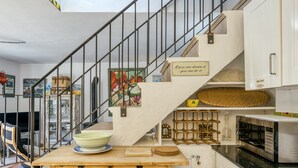 Eine Küche mit Holztisch, Mikrowelle und Treppe, an der ein motivierendes Schild hängt.
