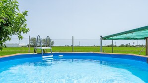 A swimming pool with a wooden deck, surrounded by a fence, and a green canopy overhead. - Country House 'Benjamin' with Lake View, Private Pool and Wi-Fi (Deltebre)