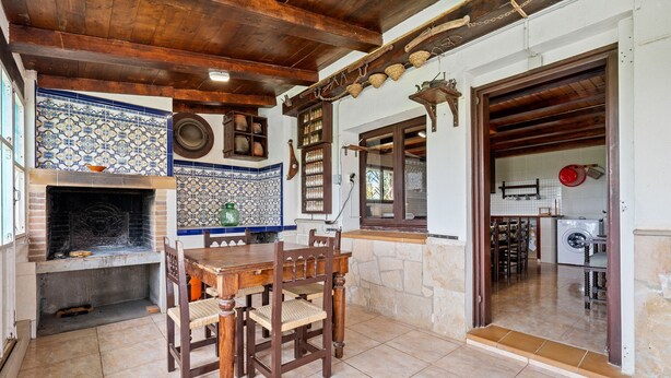 A traditional kitchen with a tiled backsplash, wooden ceiling beams, and a dining table with chairs. - Country House 'Benjamin' with Lake View, Private Pool and Wi-Fi (Deltebre)
