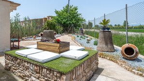 A stone structure with a grassy top, a wooden bench with cushions, and a planter with flowers. - Country House 'Benjamin' with Lake View, Private Pool and Wi-Fi (Deltebre)