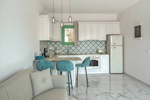 Une cuisine moderne avec des meubles blancs, une fenêtre à cadre vert et un réfrigérateur blanc.
