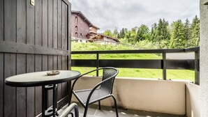 Parvekkeella on pöytä ja tuoli, ja taustalla näkyy puinen aita sekä rakennus.