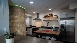 Una cocina moderna con una isla central, electrodomésticos de acero inoxidable y una pared de ladrillo decorativa.