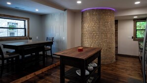 Una cocina moderna con una mesa de madera, un pilar de piedra y un ventanal con vistas a zonas verdes.