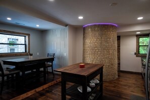 Een moderne keuken met een houten tafel, een stenen pilaar en een raam met uitzicht op groen.