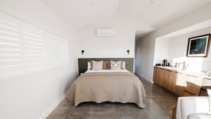 A bedroom with a bed, a wooden dresser, and a framed picture on the wall. - Ahuru House a touch of luxury - Tui Room (Mangawhai)