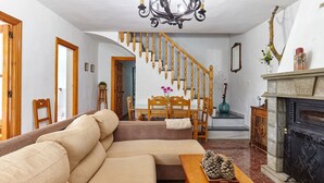 A living room with a wooden staircase, a fireplace, and a sofa. - Holiday Home 'Casa Rural La Encina' with Mountain View, Private Pool and Air Conditioning (Jaén)