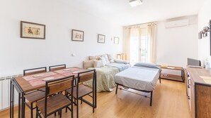 Um quarto com cama, escrivaninha, cadeira, mesa e janela com cortinas.