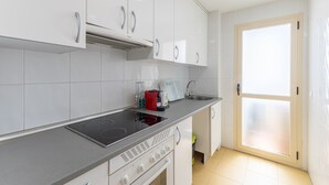 Uma cozinha moderna com armários brancos, fogão de aço inoxidável e forno embutido.