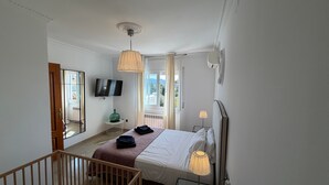 A bedroom with a bed, bedside lamp, TV, and a view of the outdoors. - Holiday Home 'Villa Mansory' with Sea View, Wi-Fi and Air Conditioning (Lloret de Mar)