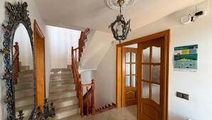 A staircase with wooden railings and a chandelier, a large ornate mirror, and a door with frosted glass panels. - Holiday Home 'Villa Mansory' with Sea View, Wi-Fi and Air Conditioning (Lloret de Mar)
