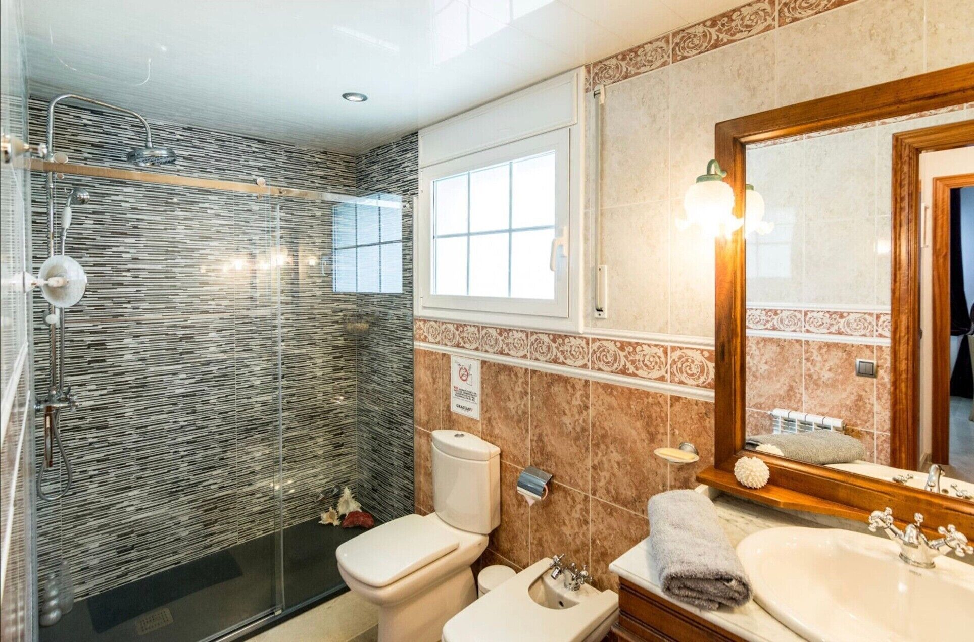 A bathroom with a shower, toilet, sink, and mirror.