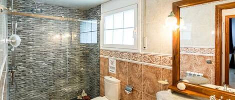 A bathroom with a shower, toilet, sink, and mirror.