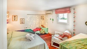 Quarto com duas camas, janela com vista, cortina com luzes de fada e decorações fixadas na parede.