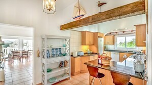 A modern kitchen with wooden cabinets, a dining area with chairs, and a view of the outdoors.