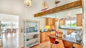 Una cucina moderna con mobili in legno, un'area pranzo con sedie e vista sull'esterno.