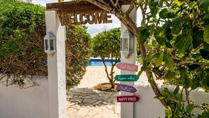 A welcome sign with directional arrows to amenities like a pool party, chillout area, and happy vibes.
