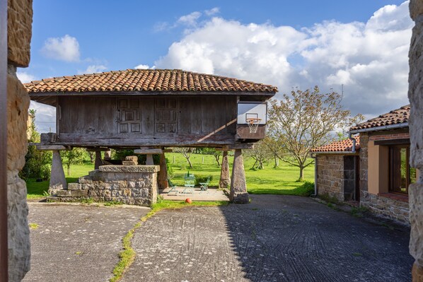 A rustic building with a tiled roof, a basketball hoop, and a stone bench. - Holiday Home 'El Prado De La Romia' with Mountain View, Private Terrace and Private Garden (Argüero Villaviciosa)