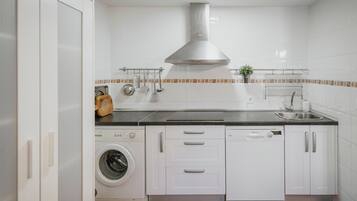 Una cocina moderna equipada con lavadora, lavavajillas y campana extractora de acero inoxidable.