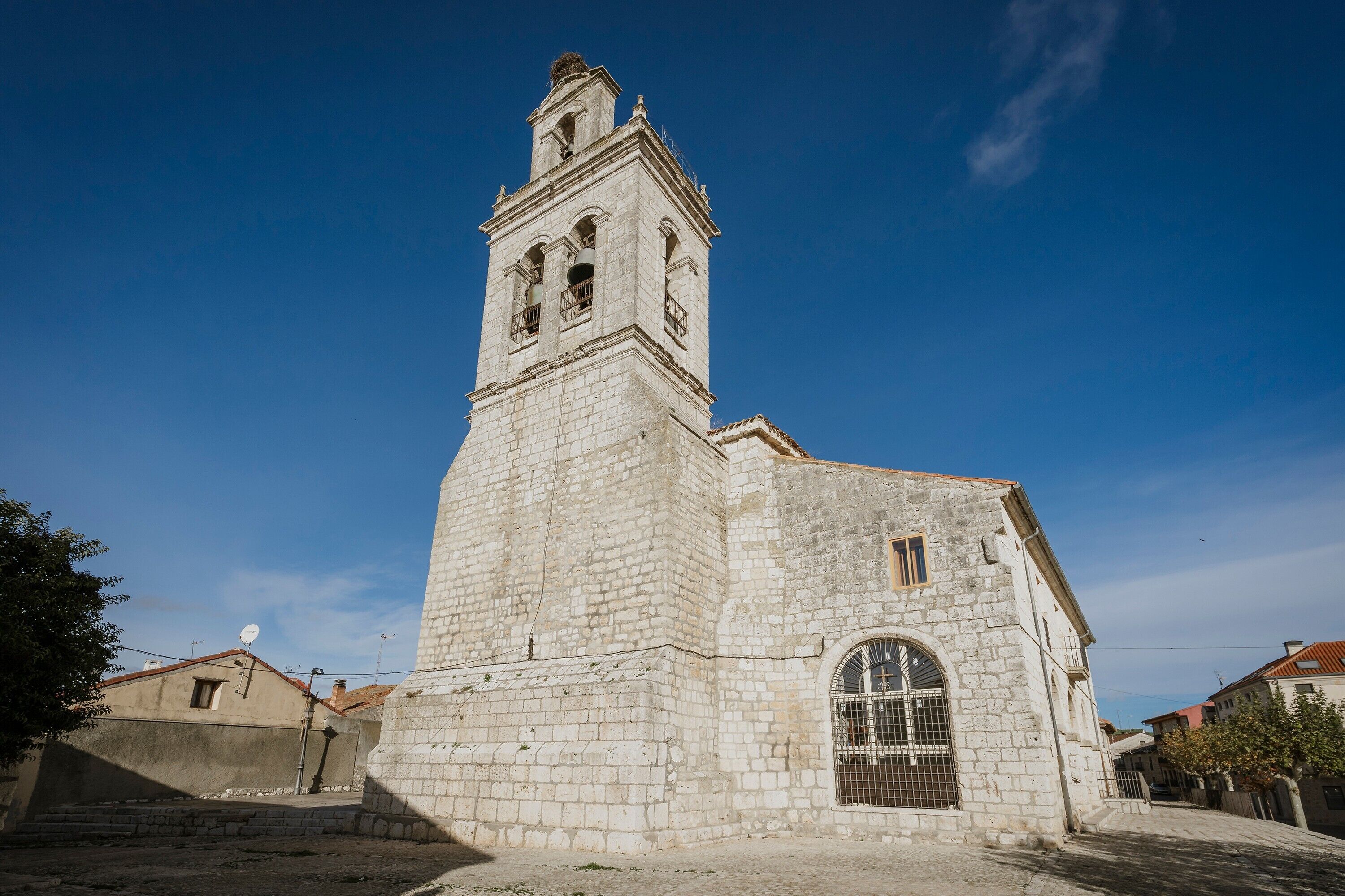 A historic stone church with a bell tower, arched windows, and a small door.