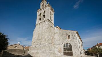 A historic stone church with a bell tower, arched windows, and a small door.