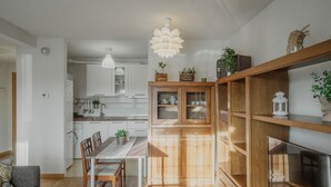 Una cocina moderna con armarios de madera, un comedor con mesa y sillas, y un televisor sobre un mueble de madera.