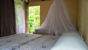Ein Schlafzimmer mit Bett, Baldachin und Blick auf Grünflächen.
