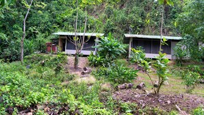 Zwei kleine, eingeschossige Gebäude, umgeben von dichter Vegetation.