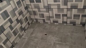 Ein Badezimmer mit gemusterten Fliesen an den Wänden und einem schlichten Fliesboden.