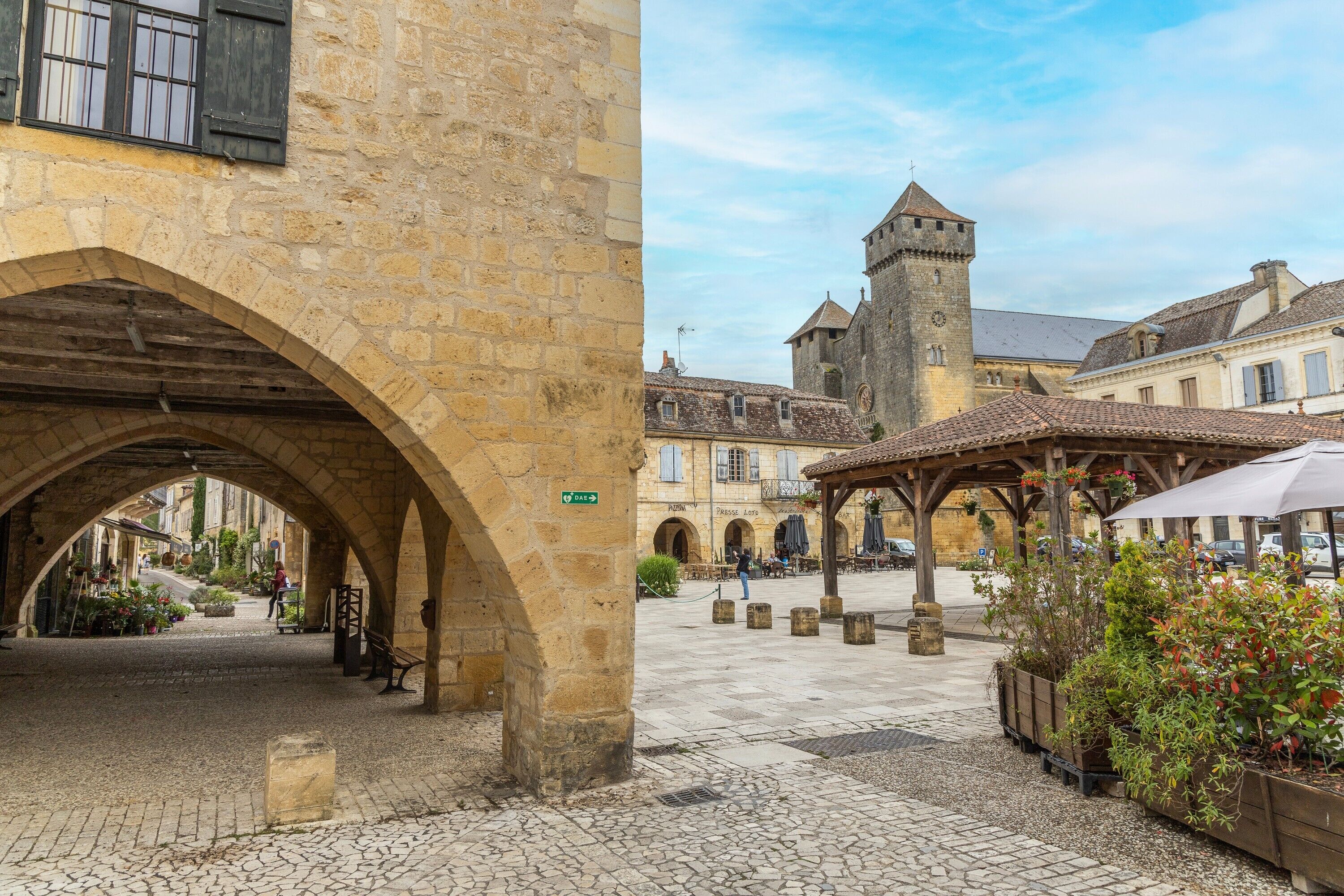 A historic stone building with an archway, a tower, and a covered outdoor seating area.
