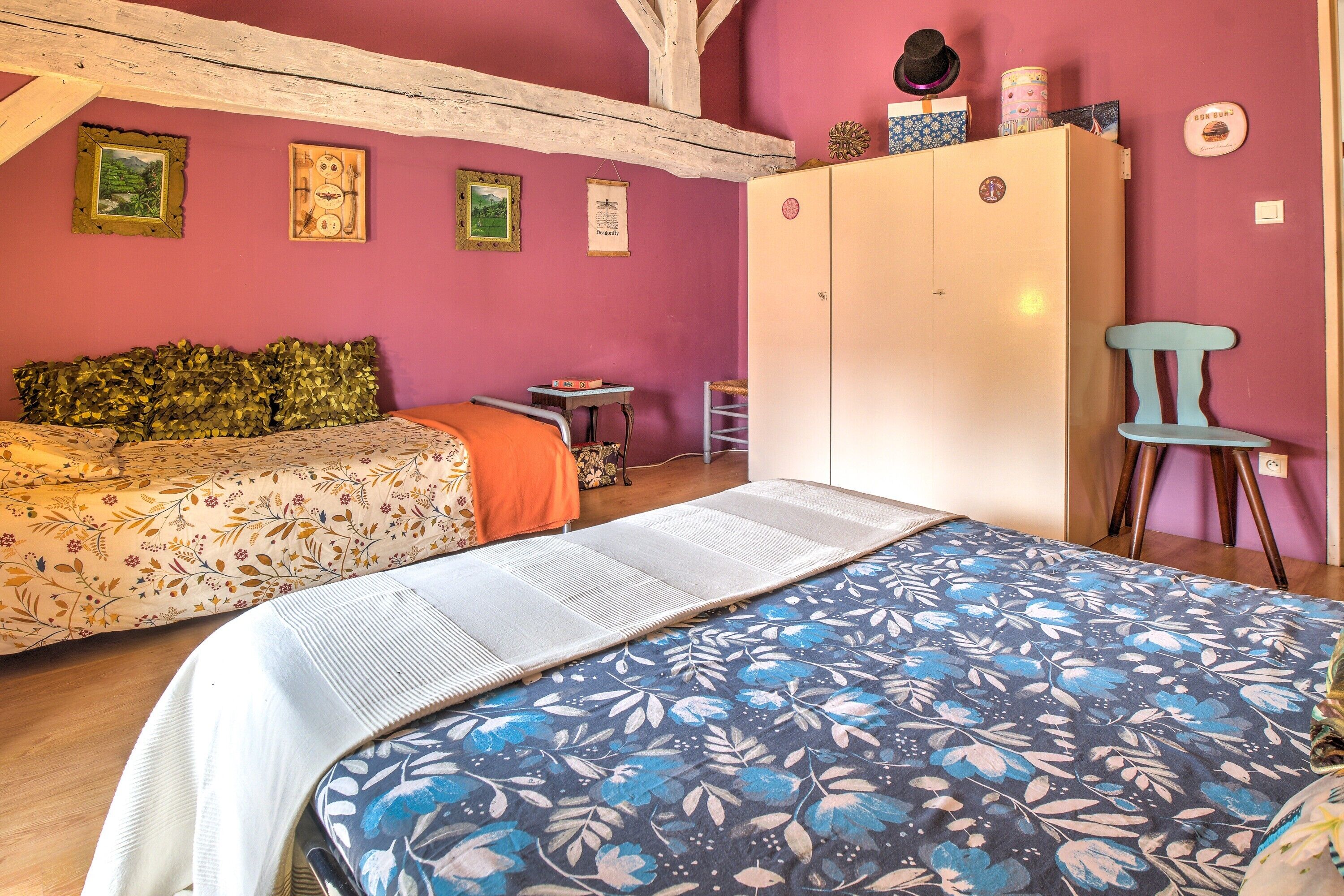 Ein Zimmer mit zwei Betten, einem Schrank, einem kleinen Tisch und einem Stuhl.