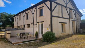 A two-story building with a balcony, a door, and a window. - Magical Stay at Il était une fois Cottage – Shared Pool and Air Conditioning (Beaumontois-en-Périgord)