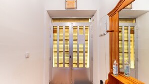 A hotel room entrance with a wooden bench, a door with a view of the outside, and a small window with blinds. - Sol y Luna Countryside Home with Pool near Toledo and Puy du Fou (Manzaneque)