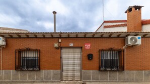 A brick building with a metal shutter door, two windows with metal bars, a chimney, and a sign that reads 'VUT.' - Sol y Luna Countryside Home with Pool near Toledo and Puy du Fou (Manzaneque)