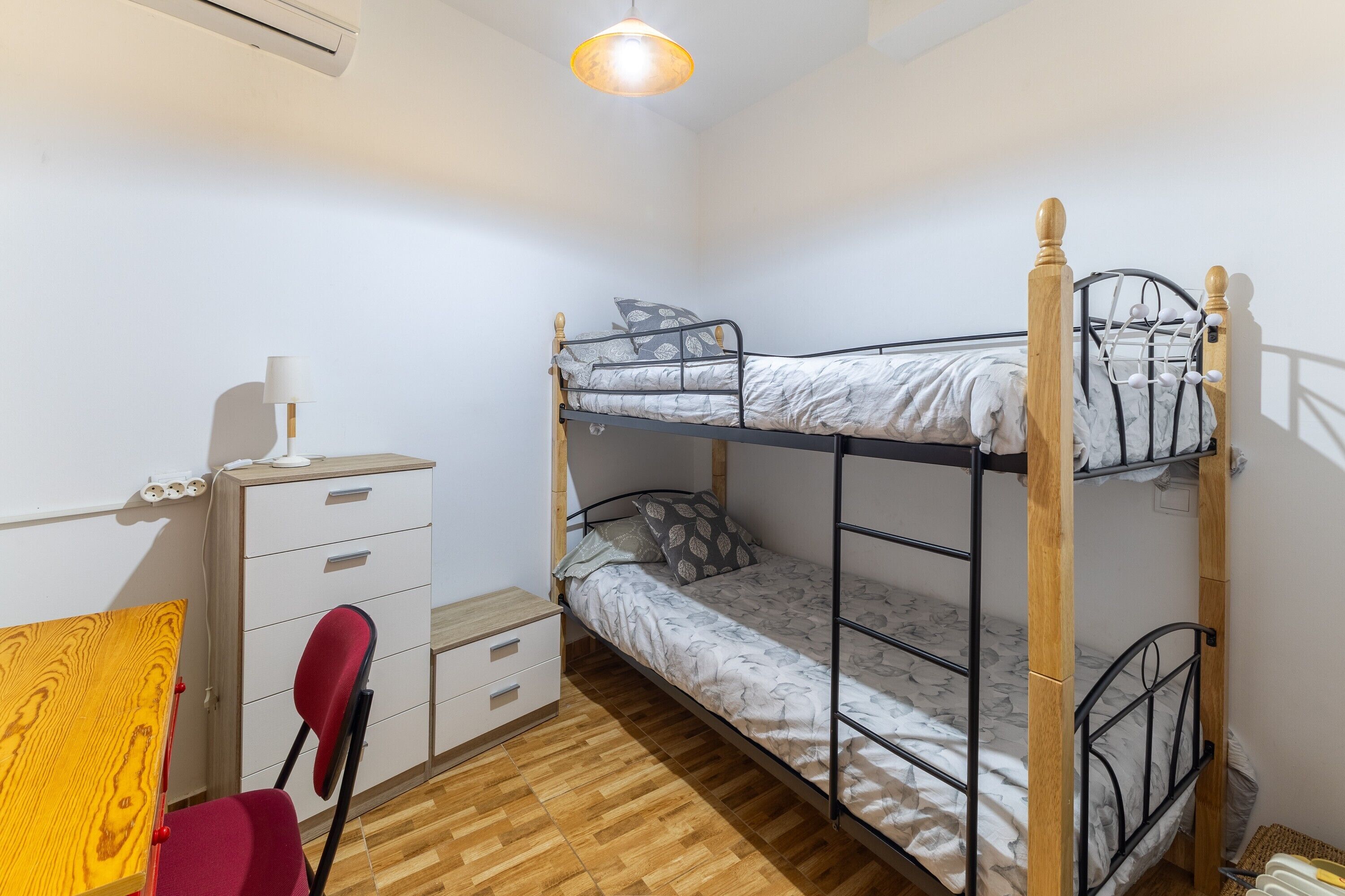 A bunk bed room with a desk, chair, and a lamp.