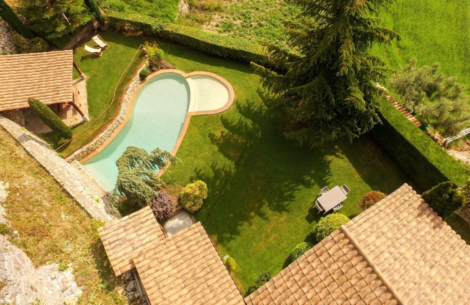 Una propiedad residencial con piscina, un patio amueblado y un césped bien cuidado.