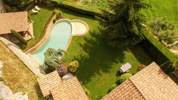 Una propiedad residencial con piscina, un patio amueblado y un césped bien cuidado.
