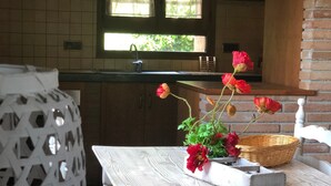 Een keuken met een raam, een spoelbak en een tafel met een bloevas.