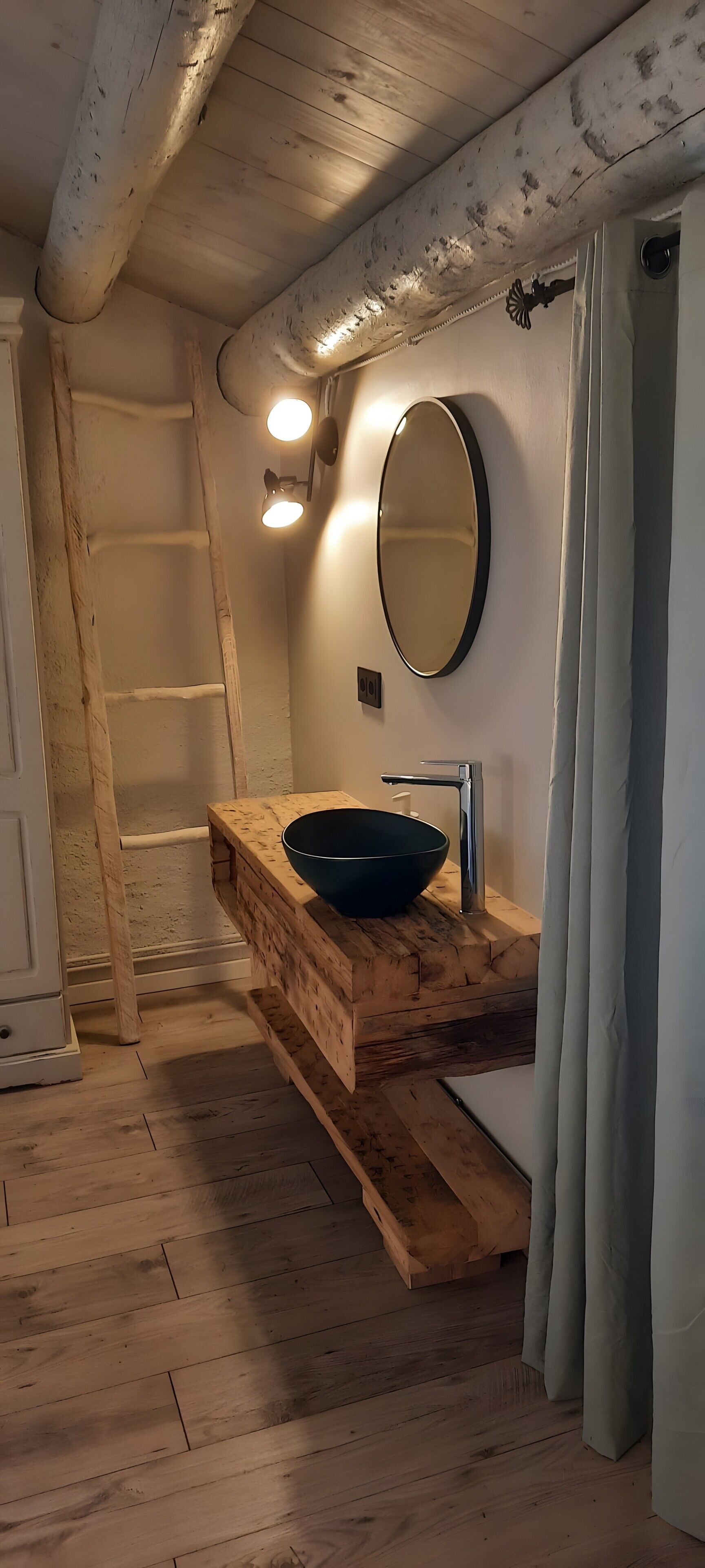 A rustic bathroom with a wooden vanity, a round mirror, and a modern faucet.
