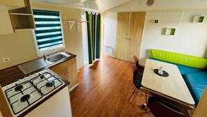 Una kitchenette compacta con estufa a gas, pileta y ventana con persianas.