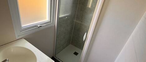 Une petite salle de bain avec une fenêtre, un lavabo et une douche.