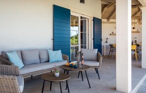 A cozy outdoor seating area with a wicker sofa and chairs, a small round table, and a potted plant. - Beautiful home in Maruzini with sauna (Maruzini)