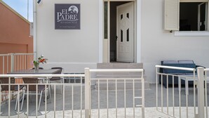 A hotel entrance with a sign, a door, and a window with shutters.